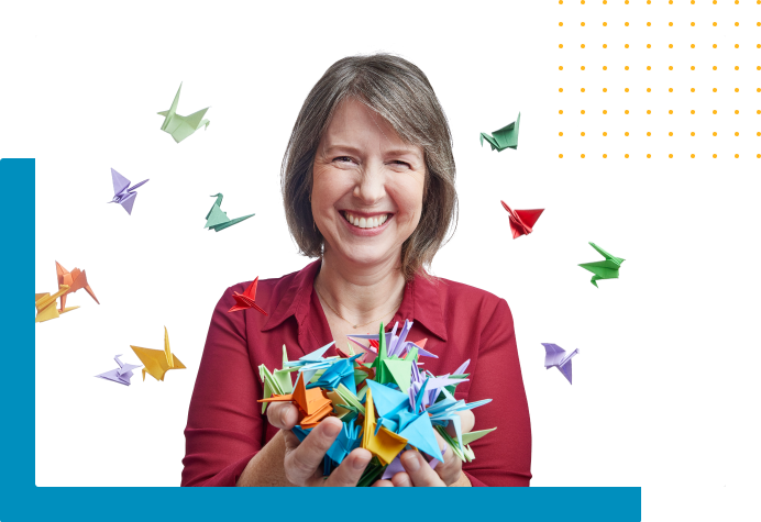 Woman smiling holding and surrounded by colorful origami 
